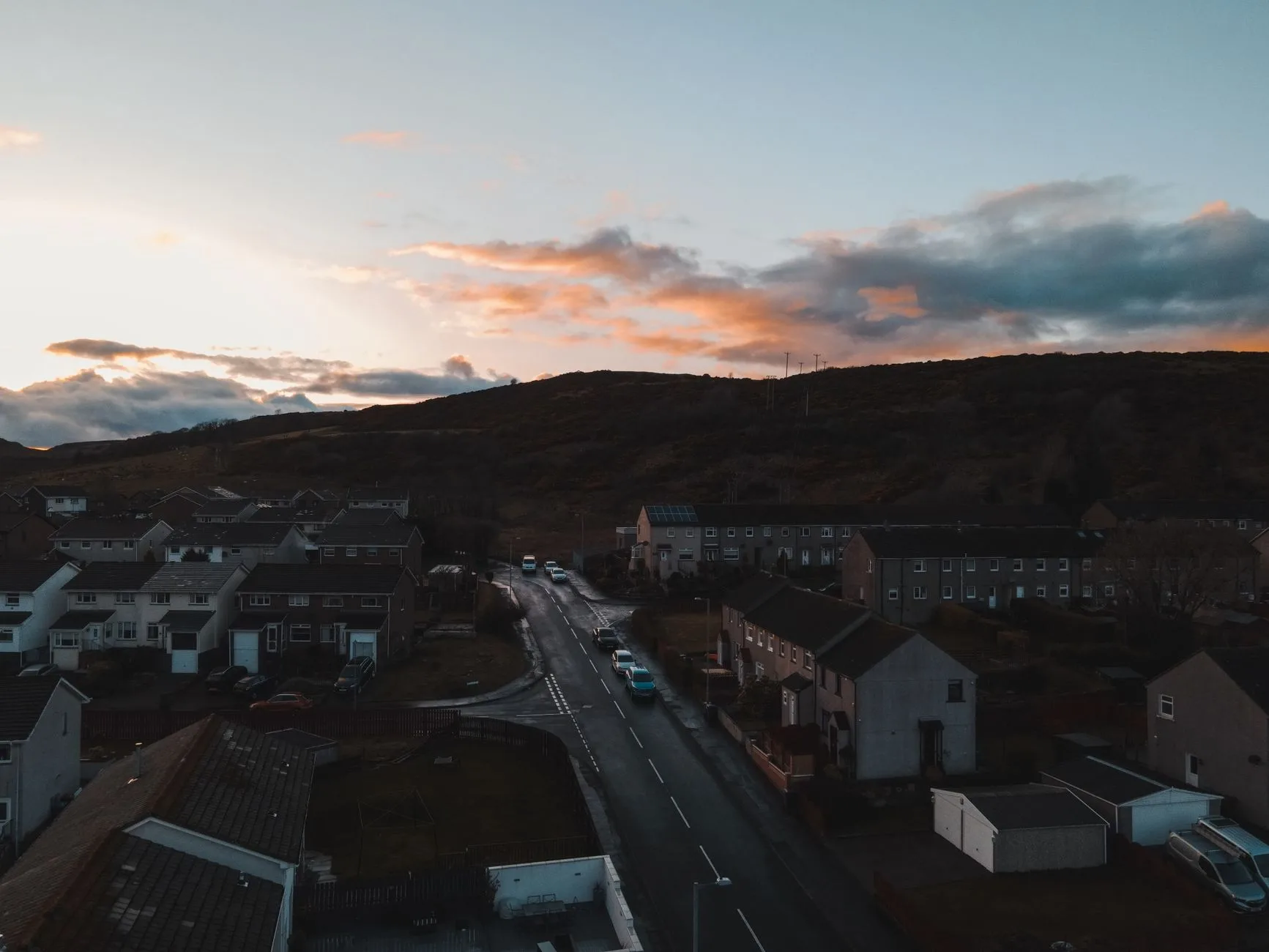 A small town below hills at dusk