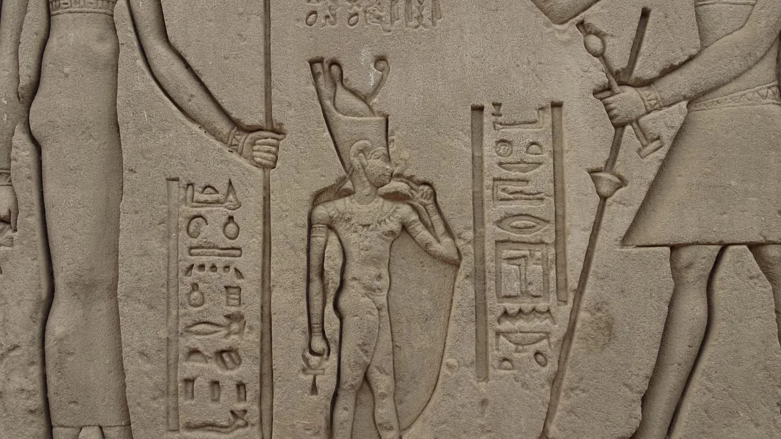 Intricate stone relief of ancient Egyptian figures and hieroglyphs.