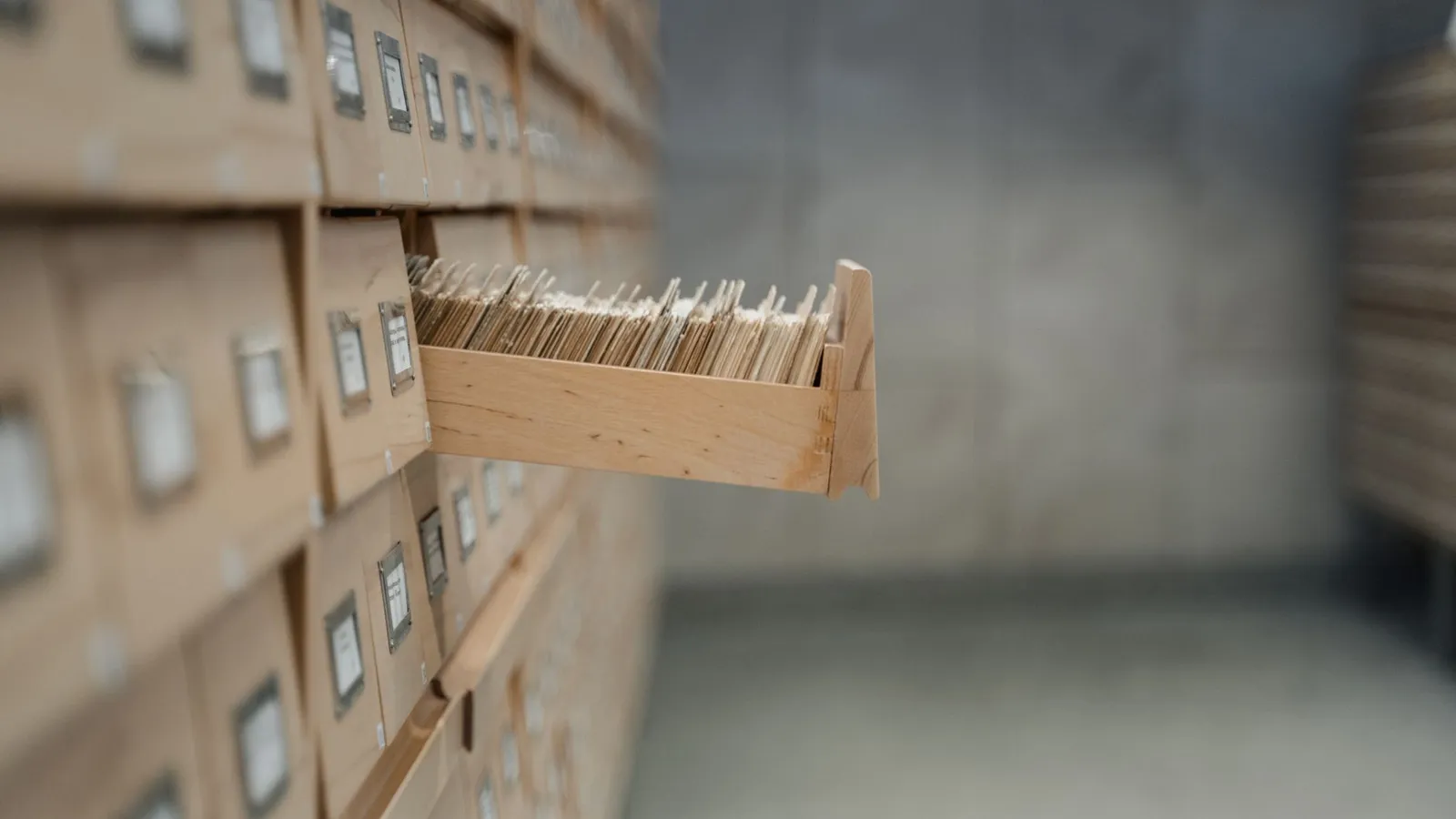 A vintage card catalog drawer in an archive library setting, highlighting organization and history.