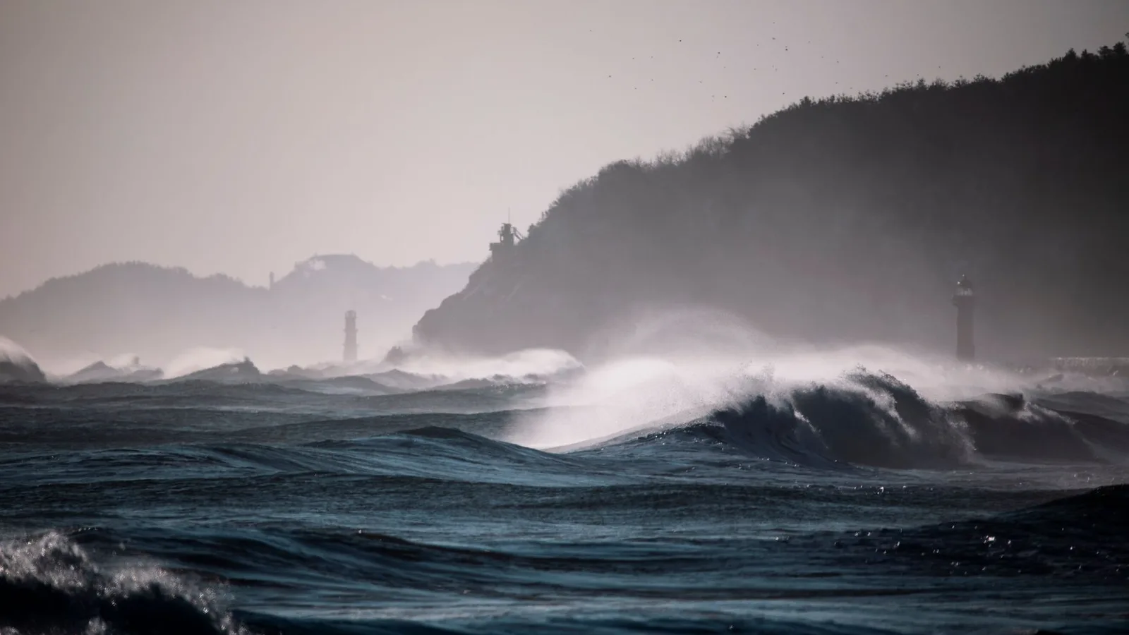 Waves breaking against the coast near a lighthouse